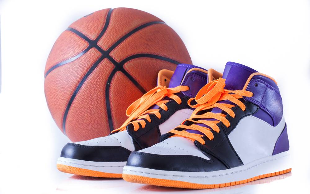 Visoki košarkarski čevlji s košarkarsko žogo v ozadju.
